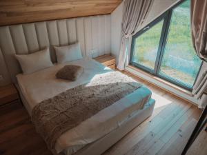 a bed in a room with a large window at Vama Chalet in Vama Buzăului +63 photos