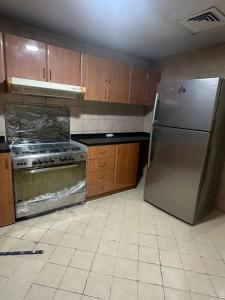 uma cozinha com um frigorífico de aço inoxidável e armários de madeira em The Ajman Best Furnished Room em Ajman