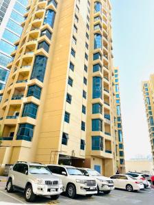 um grande edifício com carros estacionados em um estacionamento em The Ajman Best Furnished Room em Ajman