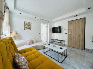 a living room with a yellow couch and a table at Superbe appartement avec piscine in Tunis