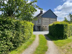 an old stone house with two hedges in front of it at Le Moulin de Mautheville in Grainville-la-Teinturière