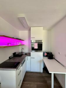 kuchnia z białymi szafkami i różowym oświetleniem w obiekcie Enna Apartment B Meerblick perfect location w Medulinie