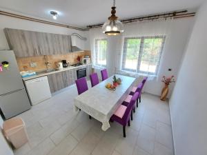 a kitchen and dining room with a table and purple chairs at Spacious apartment in Pula for 6 persons and with a big swimming pool in Pula