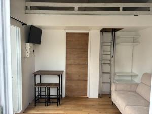 a room with a door and a table and a couch at Studio cosy avec piscine à 10 min Hossegor in Saint-Vincent-de-Tyrosse