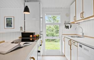 a kitchen with white cabinets and a book on the counter at 3 Bedroom Gorgeous Home In Slagelse in Slagelse