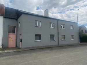 a white building with a pink door on a street at Guesthouse Sprinysem in Zedelgem