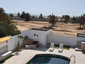 Résidence Mimosas avec piscine et vue de mer في تاجورميس: حديقه خلفيه بها مسبح ومنزل