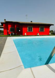una casa roja y una piscina frente a una casa roja en La Villa degli Uliveti, en Fabrica di Roma