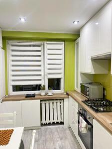 a kitchen with white cabinets and green walls at Apartament Bella Zdrój in Głuchołazy