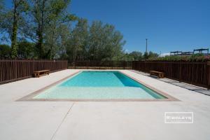 a swimming pool with two benches and a fence at Superbe T3 climatisé avec WIFI à 400m de la plage in Vias
