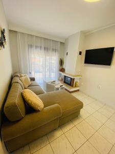 a living room with a couch and a tv at PerAmore Apartment in Nea Peramos