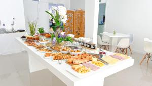 a buffet of food on a white table at Pousada da Bia Praia in Penha +15 photos