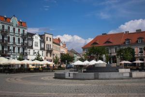 a street with tables and umbrellas in a city at Stare Gniezno Centrum Miasta in Gniezno