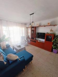 Una sala de estar con un sofá azul y un televisor en Apartamento Alarve, en Nerja