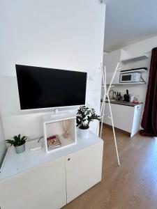 a white entertainment center with a flat screen tv on a wall at Formai Living apartments in Trento