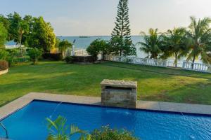 a blue swimming pool in a yard with the ocean at Sound of the Sea Villa PD in Port Dickson