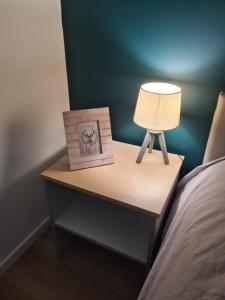 a bedside table with a lamp and a picture on it at Appartement au pied des pistes avec grande terrasse in Orbey +33 photos