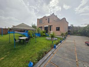 a house with a yard with a table and umbrella at Luxueuse Villa Tedili Mesfioua in Marrakech