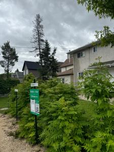 a green sign in front of a yard with bushes at Walking distance to St Boniface, easy parking in Winnipeg