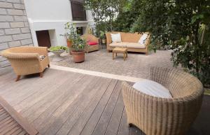 Un patio con sillas y muebles de mimbre sobre una terraza de madera. en Garden pool Beach rest secure, en La Ciotat