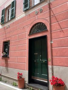 a red brick building with a green door and flowers at Casa Mia Bogliasco Mare & Centro in Bogliasco