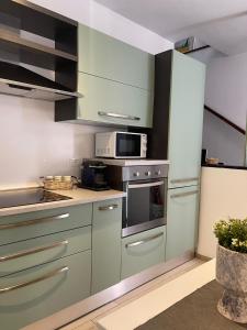 Kuchnia z zielonymi szafkami i kuchenką mikrofalową w obiekcie Casa Mia Sea&Center w mieście Bogliasco