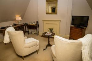 uma sala de estar com duas cadeiras e uma televisão em Horsted Place Hotel em Uckfield