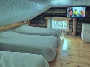 a bedroom with three beds and a tv on the wall at KeloValkea Äkäslompolo in Äkäslompolo