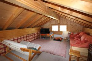 a room with a attic with a couch and a tv at Le Gros Pâquier in La Lécherette