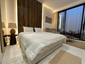 1 dormitorio con 1 cama blanca grande y sala de estar en Divon Chalets, en Buraidah