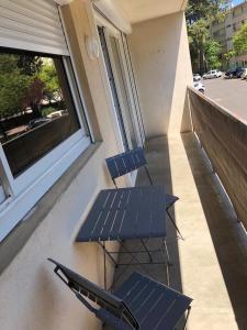 two chairs and a table on a balcony with a window at Chambre avec salle d'eau privée dans appartement partagé 200 m du tram in Montpellier