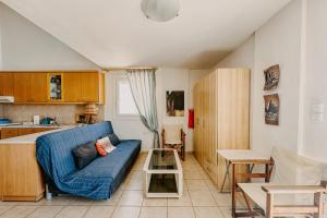 ein Wohnzimmer mit einer blauen Couch und einer Küche in der Unterkunft Refresh & Relax Residencies in Finikas