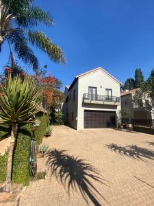 a white house with a palm tree and a driveway at BLessing at Lynnwood in Pretoria