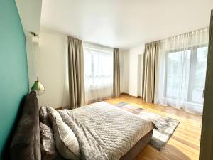 a bedroom with a bed and two large windows at Spacious Family Apartment by the Sea in Jūrmala