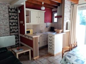 a kitchen with red walls and white cabinets at Le Pas de l'Âne - Les Apparts du Sancy in Chastreix