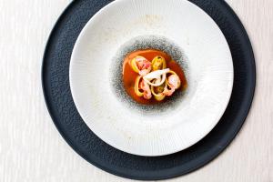 a white plate with a bowl of food on a table at Zen Hotel Versilia in Marina di Pietrasanta