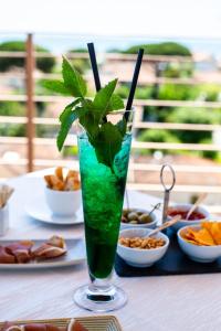 a green drink in a glass on a table with food at Zen Hotel Versilia in Marina di Pietrasanta