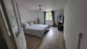 a bedroom with a bed and a tv and a window at O'Haras in La Chapelle-de-la-Tour