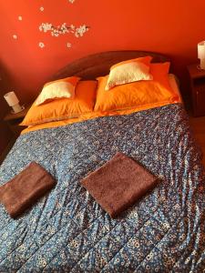 a bed with orange sheets and pillows on it at Gemini apartman in Hajdúszoboszló