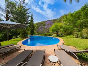 einen Pool mit Stühlen und einem Sonnenschirm in der Unterkunft Cubo's Villa Las Lagunas de Azahar High Privacy in Coín