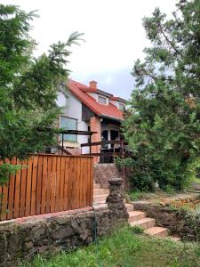 a house with a wooden fence and some trees at Fig Tree house in Lovas