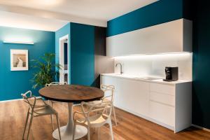 a kitchen with blue walls and a table and chairs at Camoma Aparthotel - Suites Apartments in Jesolo