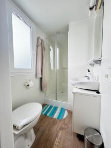 a white bathroom with a toilet and a shower at Mobile Homes Relax Park Umag in Umag