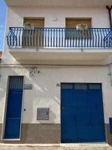 Edificio con 2 puertas azules y balcón en Il cappero casa vacanze, en Stazzo