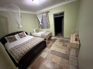 a bedroom with a bed and a chair and a window at Blasto & Esita Cottages in Bunamwaya