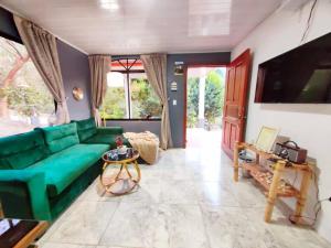 a living room with a green couch and a tv at Hermosa Casa en Medio de la Naturaleza Monteverde in Monteverde Costa Rica
