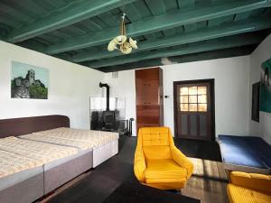 a bedroom with a bed and a yellow chair at Modrá chalupa in Pliešovce