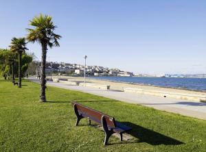 a park bench sitting in the grass near the water at Piso 4 dormitorios playa sada in Sada