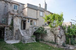 an old stone house with stairs in front of it at Apartman Nives in Lubenice