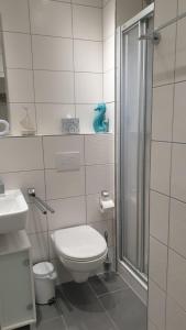 a white bathroom with a toilet and a shower at Haus Seelord am Weststrand in Norderney